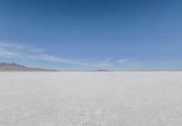 a barren area with mountains in the background and no clouds in the sky, with only one person visible