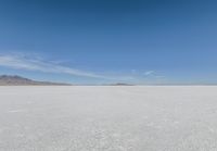 a barren area with mountains in the background and no clouds in the sky, with only one person visible