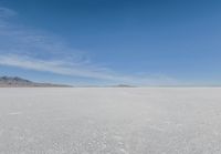 a barren area with mountains in the background and no clouds in the sky, with only one person visible