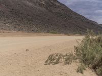 a small vehicle traveling across a barren road between some large rocks and boulders on one side