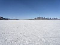 large expanse of white sand, with mountains in the distance in distance is blue sky