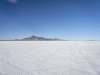large expanse of white sand, with mountains in the distance in distance is blue sky