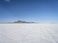 large expanse of white sand, with mountains in the distance in distance is blue sky