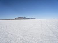 large expanse of white sand, with mountains in the distance in distance is blue sky