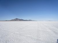 large expanse of white sand, with mountains in the distance in distance is blue sky