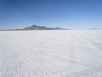 large expanse of white sand, with mountains in the distance in distance is blue sky