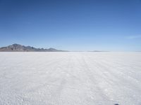 large expanse of white sand, with mountains in the distance in distance is blue sky