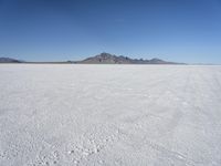 large expanse of white sand, with mountains in the distance in distance is blue sky