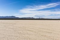 an empty desert landscape with sparse plants and mountains in the background on a sunny day