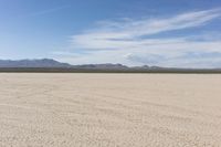 an empty desert landscape with sparse plants and mountains in the background on a sunny day