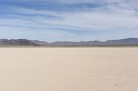 an empty desert landscape with sparse plants and mountains in the background on a sunny day