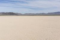 an empty desert landscape with sparse plants and mountains in the background on a sunny day