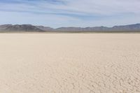 an empty desert landscape with sparse plants and mountains in the background on a sunny day