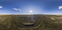 a panoramic view of an abandoned quarry in a desert landscape with mountains in the background