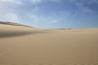 a lone person is walking in the middle of a desert with sand, one foot on the ground