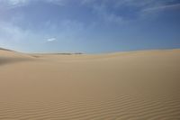 a lone person is walking in the middle of a desert with sand, one foot on the ground