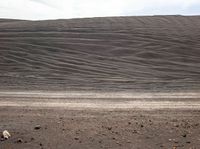 the desert has large mounds of rocks and gravel on the ground, one black horse in the foreground