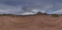 an image of a sky over the ground and rocks on a hill under stormy skies