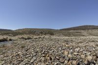 a view from the ground in the desert with rocky terrain and blue skies above,