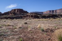 a desert with rocky terrain against a clear blue sky, in front of a big rock mountain