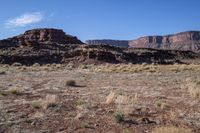 a desert with rocky terrain against a clear blue sky, in front of a big rock mountain