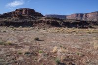 a desert with rocky terrain against a clear blue sky, in front of a big rock mountain