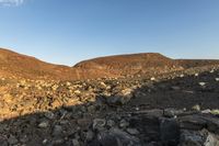 there are large rocks everywhere in the desert, and the blue sky is clear at dawn