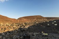 there are large rocks everywhere in the desert, and the blue sky is clear at dawn