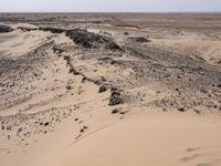 a truck on a dirt road in the desert with rocks and stones on the ground