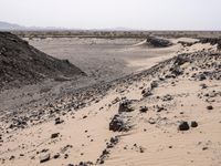 a truck on a dirt road in the desert with rocks and stones on the ground