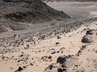 a truck on a dirt road in the desert with rocks and stones on the ground