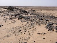 a truck on a dirt road in the desert with rocks and stones on the ground