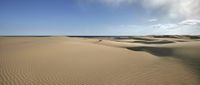 the large desert is full of dunes and clouds in the sky and water on the beach