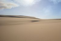 two people are riding their horses in the desert sand hills are empty of vegetation and are separated by sand