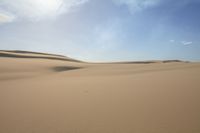 two people are riding their horses in the desert sand hills are empty of vegetation and are separated by sand