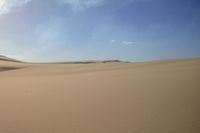 two people are riding their horses in the desert sand hills are empty of vegetation and are separated by sand