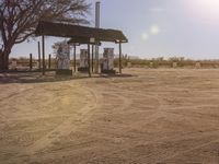 a dirt road and a gas station with several fuel pumps on it in the desert