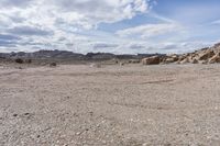 a stop sign in the middle of a rocky desert area with mountain range in the distance