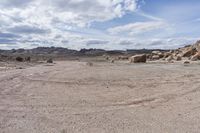 a stop sign in the middle of a rocky desert area with mountain range in the distance