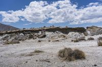 an image of a desert with very sparse ground and rock formations in the background of a vast mountainous area