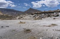 an image of a desert with very sparse ground and rock formations in the background of a vast mountainous area