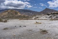 an image of a desert with very sparse ground and rock formations in the background of a vast mountainous area