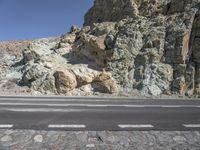 a motorcycle is traveling past a rock formation in the mountains along a road between two empty road divider