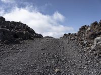 an open area is dotted with rocks and boulders, with clouds behind them - -