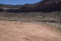 a large open barren area with rocks and scrub brush in the background and cliffs in the background