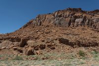 a rock outcropping in the desert area with shrubs and rocks around it