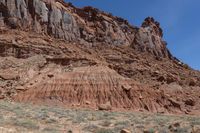 a rock outcropping in the desert area with shrubs and rocks around it