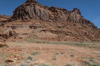 a rock outcropping in the desert area with shrubs and rocks around it