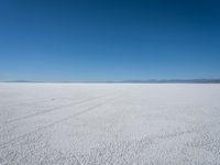 a lone snowmobile is moving across an open desert field with the mountains in the background