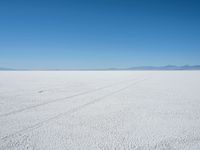 a lone snowmobile is moving across an open desert field with the mountains in the background